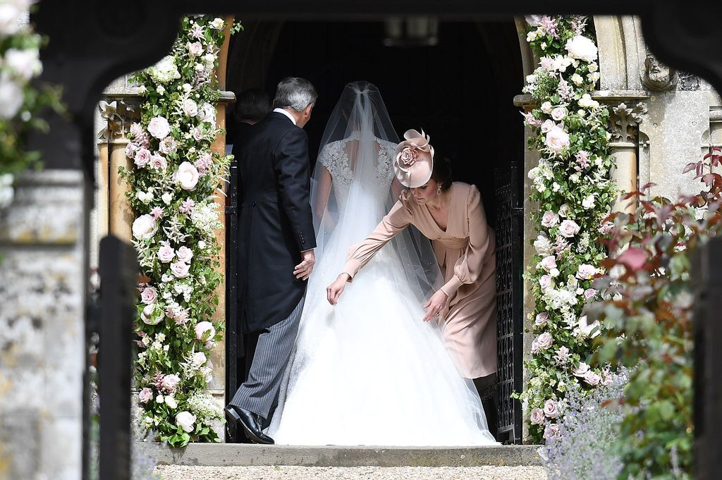 Princess Kate adjusting the train of Pippa Middleton's wedding dress