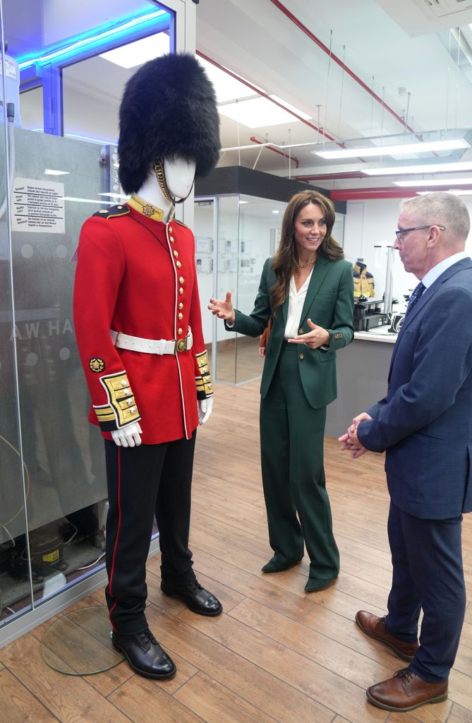 Princess Kate looks at a Guardsman scarlet tunic during a visit to AW Hainsworth