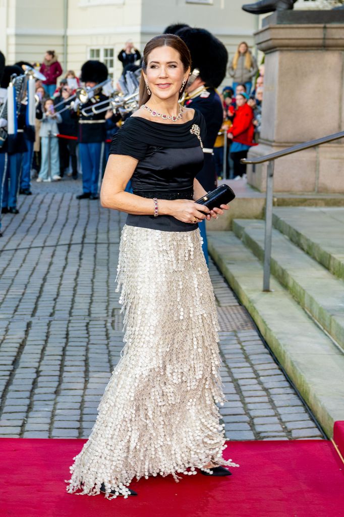 queen mary on red carpet in black satin top and silver skirt 