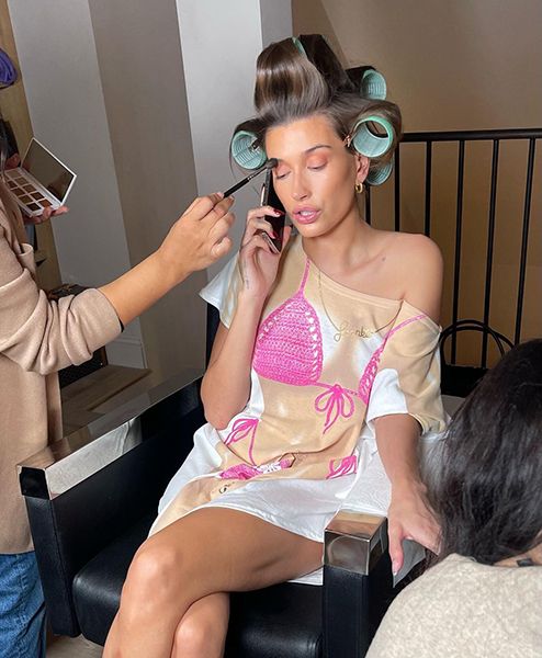 Hailey Bieber Gets Her Makeup Done While Wearing A Joke Bikini Top