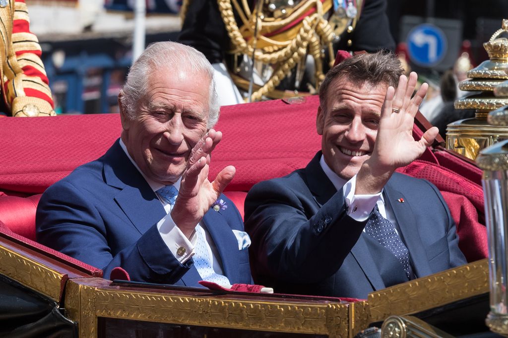 King Charles and Emmanuel Macron waving from a red-trimmed carriage