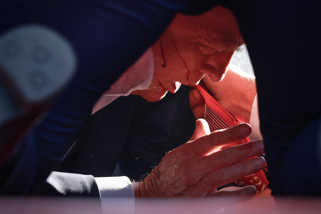 Donald Trump is shown covered by U.S. Secret Service agents after an incident during a rally 