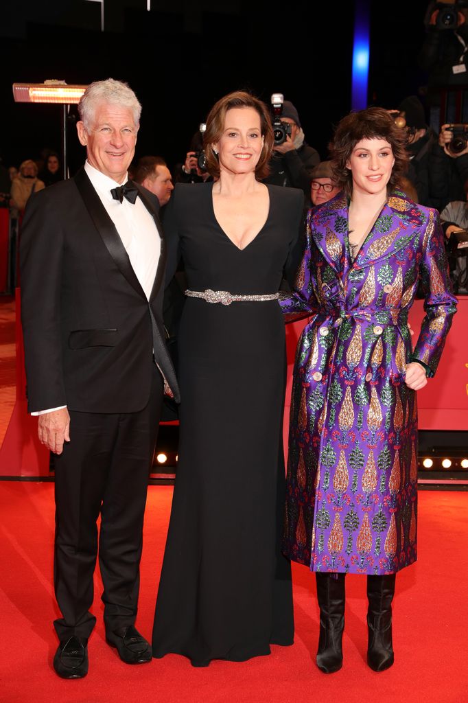 Sigourney Weaver in black dress with husband Jim Simpson in black suit and child Shar Simpson in purple dress on red carpet at the opening ceremony and "My Salinger Year" premiere during the 70th Berlinale 