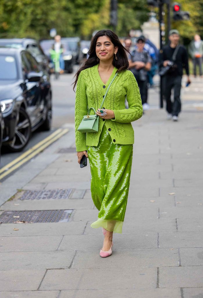 A guest wears green cardigan, sequined skirt, Hermes bag, ring outside Emilia Wickstead during London Fashion Week September 2024 