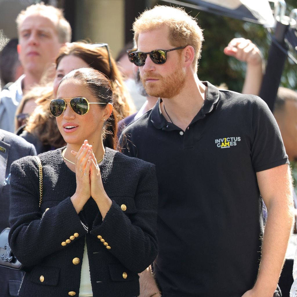 Meghan Markle e o príncipe Harry em trajes pretos durante os Jogos Invictus