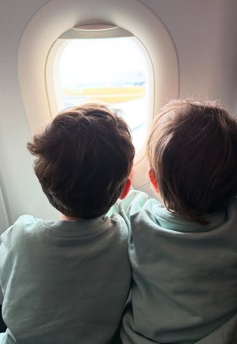 Two young children looking out of the window on an aeroplane