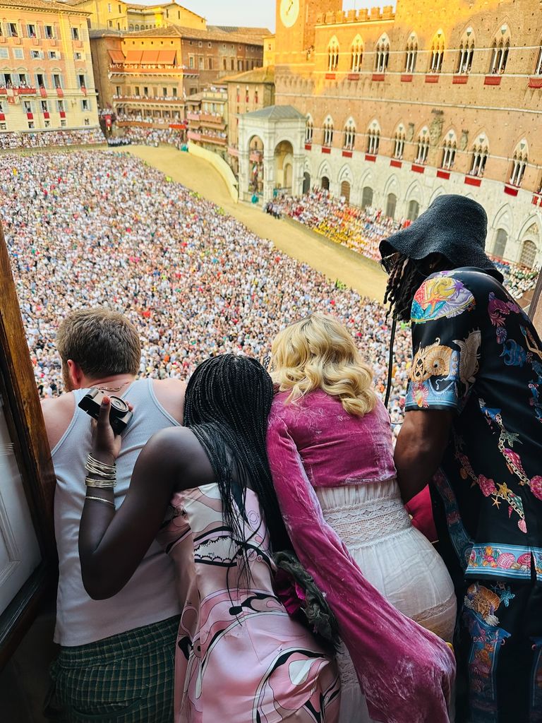 photo of the back of madonna and her children watching horse race in italy from balcony