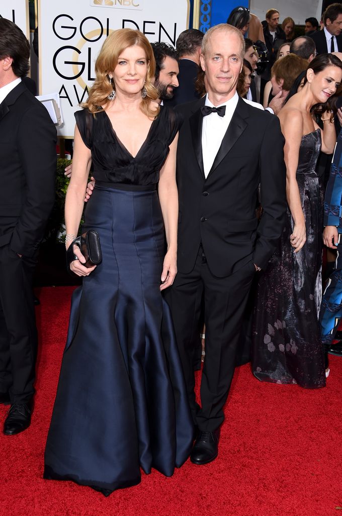 Rene Russo dans une robe bleu marine à col en V et son mari Dan Gilroy en costume et nœud papillon.