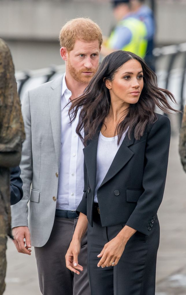 Prince Harry raising his eyebrows behind Meghan Markle