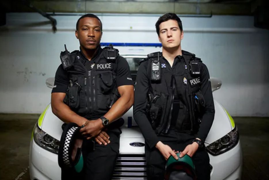 Ashley Walters and Jacob Ifan sitting on a police car
