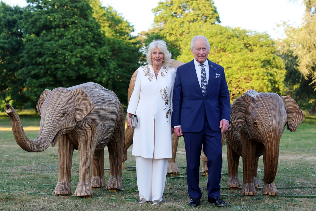 Ratu Camilla dan Raja Charles berdiri di antara gajah kayu