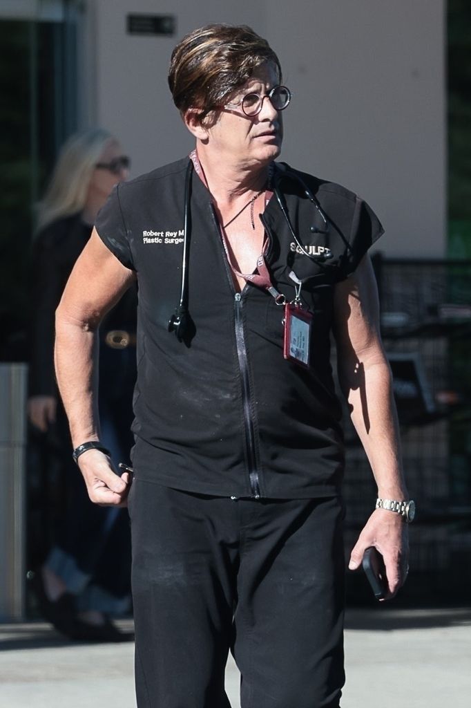 Robert rey walking in scrubs, messy hair and glasses