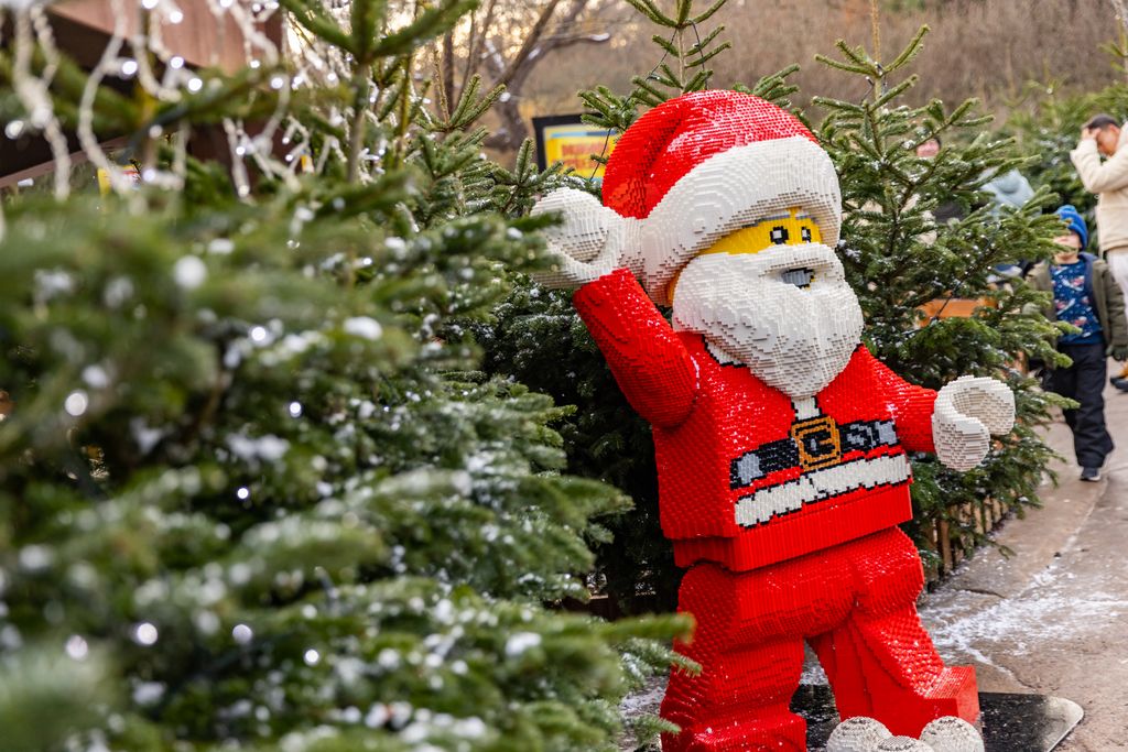 Lego Father Christmas waving standing next to a row of snow-covered Christmas trees