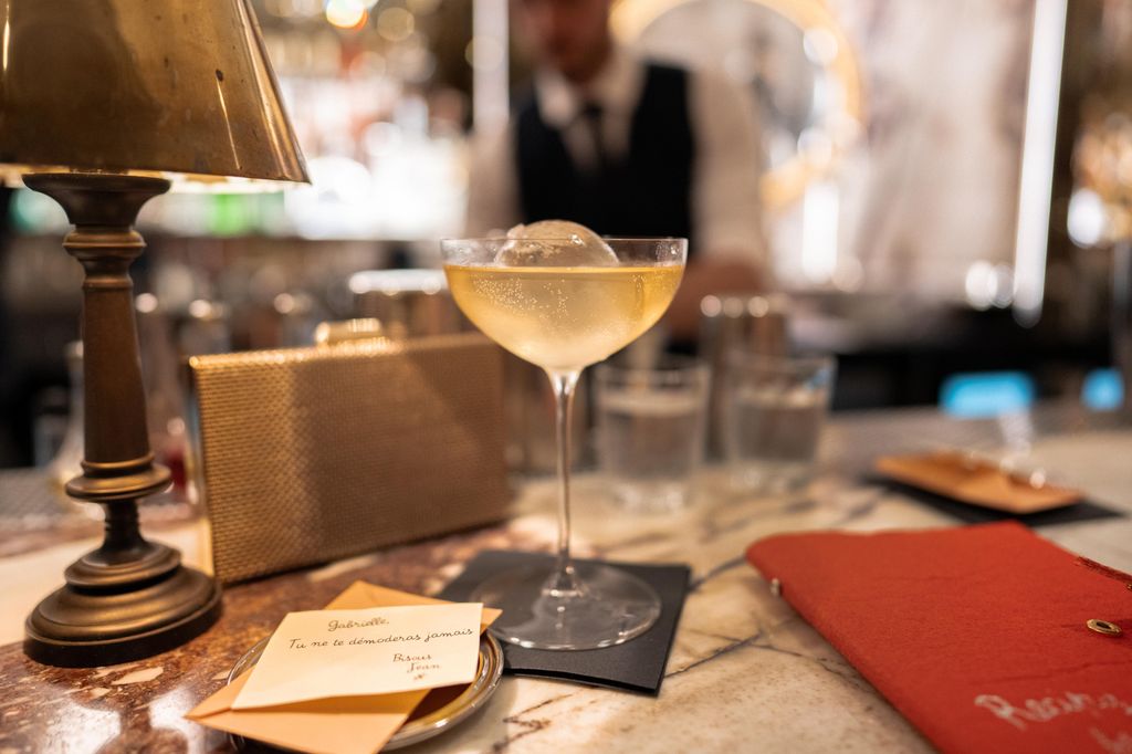 Cocktail in a glass with round ice ball sitting on a bar 