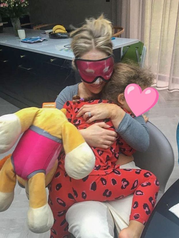 Katie Piper in an eye mask with a young girl sleeping on her