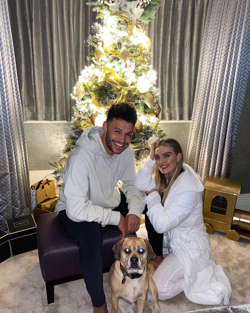 Perrie and alex smiling in front of christmas tree