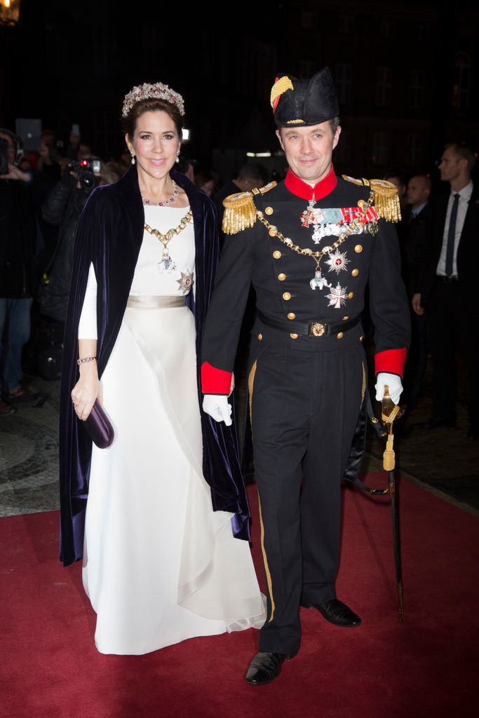Crown Princess Mary of Denmark in a white dress and velvet cape with her husband