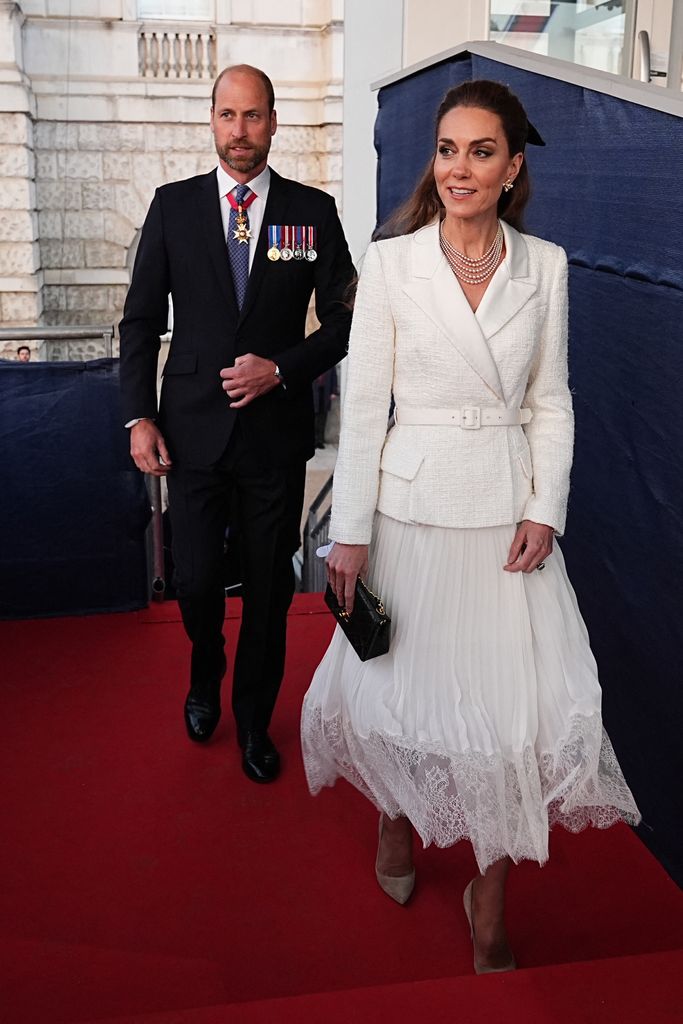 Prince William in suit and Kate wearing white blazer and skirt at VE Day concert