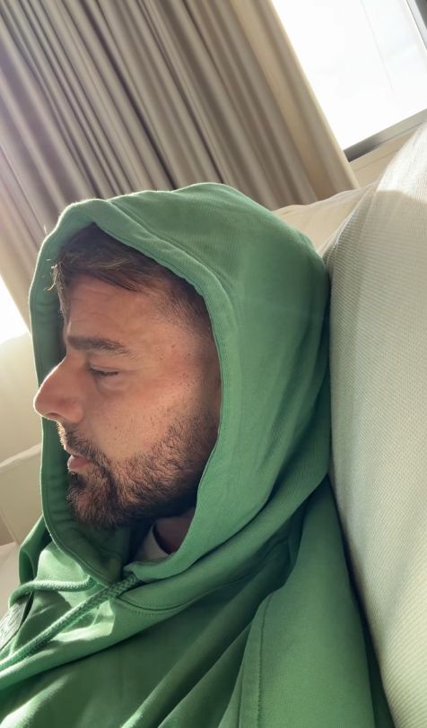 Ricky Martin in a green hoodie inside a white room
