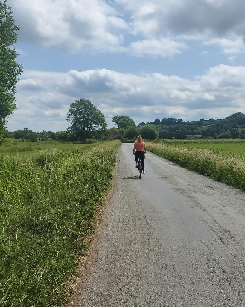 Femme sur un vélo à vélo sur une route doublée d'arbre