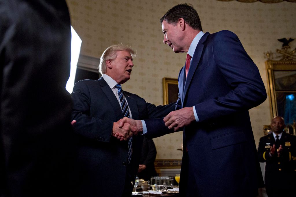 U.S. President Donald Trump (C) shakes hands with James Comey, director of the Federal Bureau of Investigation (FBI) in 2017