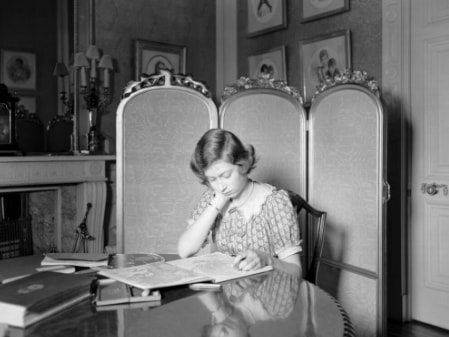 Queen Elizabeth in black and white reading at her desk