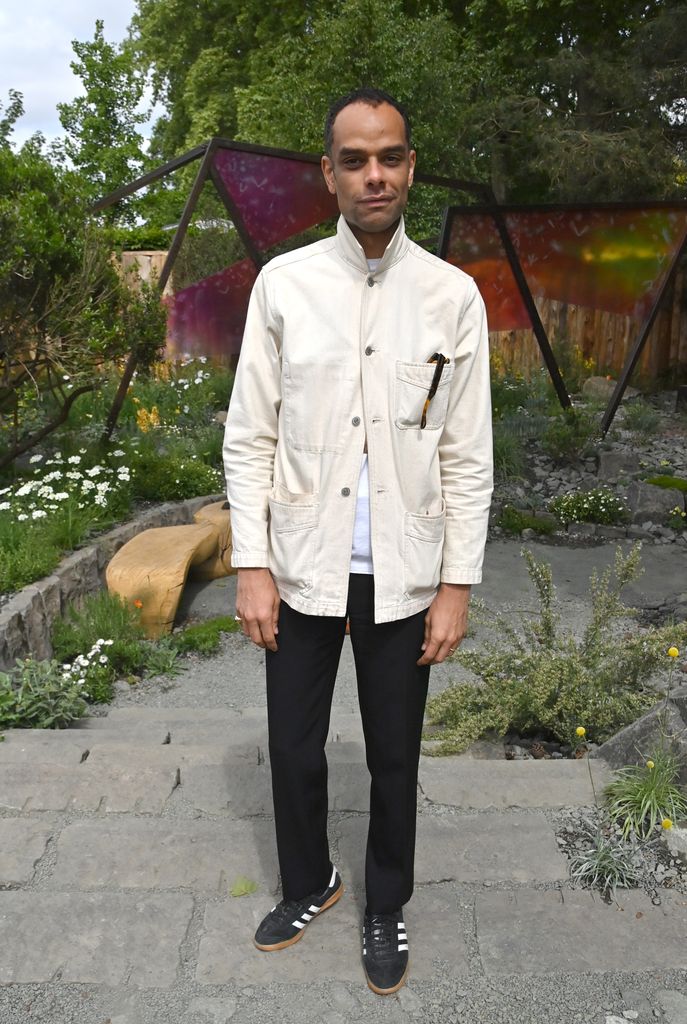 Raven Smith wears a white button-up utility jacket, black trousers and Adidas sneakers at Chelsea Flower Show.