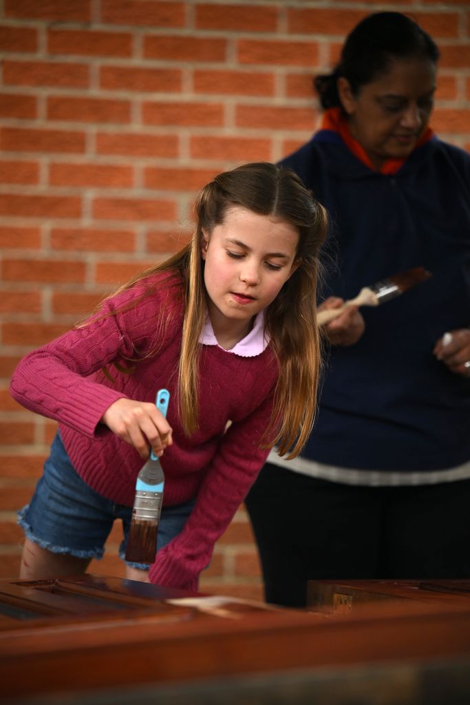 Princess Charlotte helps stain some wood at the scout hut