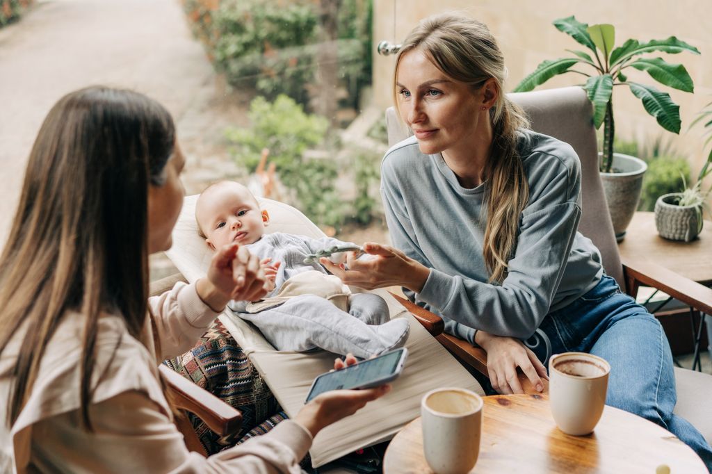 Women in a cafe holding hands with a baby