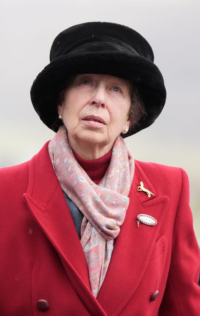 Princess Anne wearing red coat, black hat and pearls