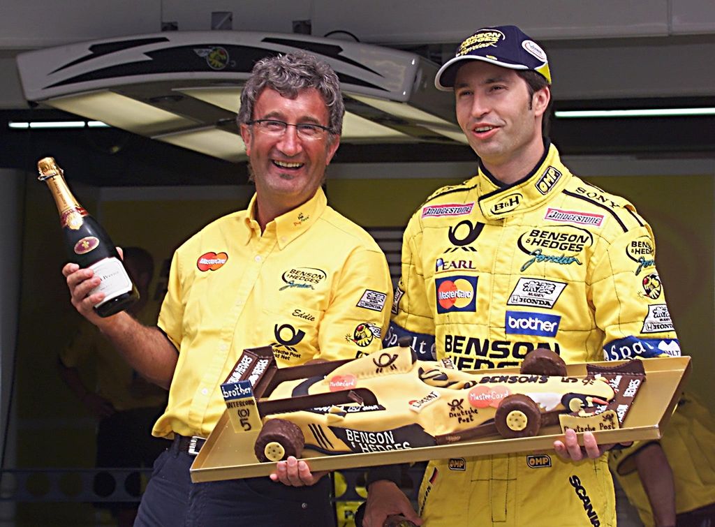 Eddie Jordan with a bottle of champagne standing with Heinz-Harald Frentzen