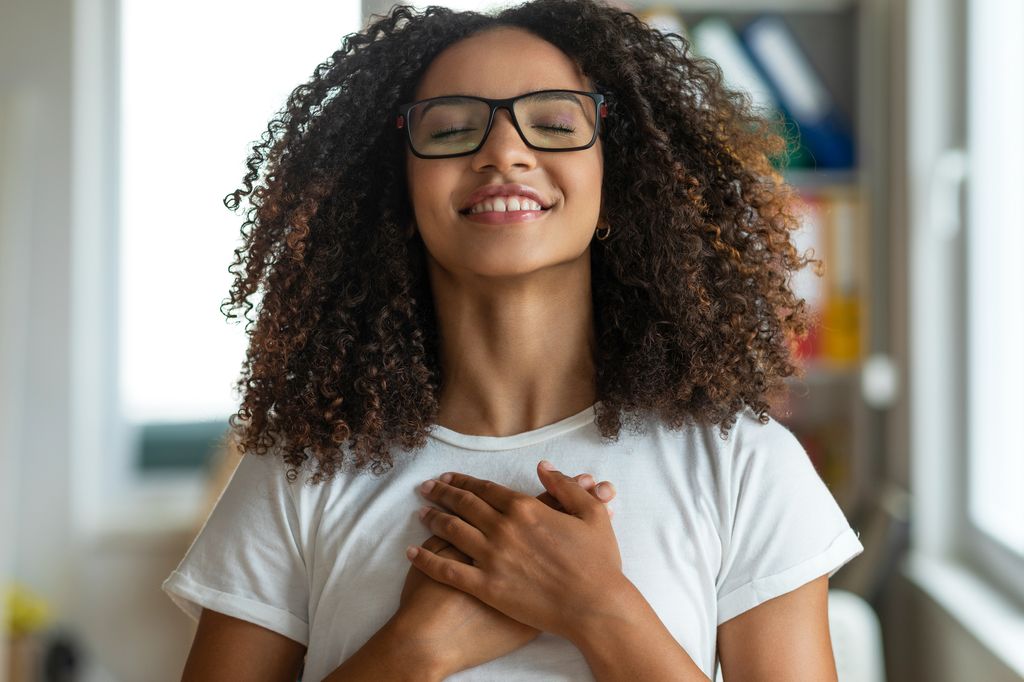 Young woman with her hands on her heart smiling with her eyes closed