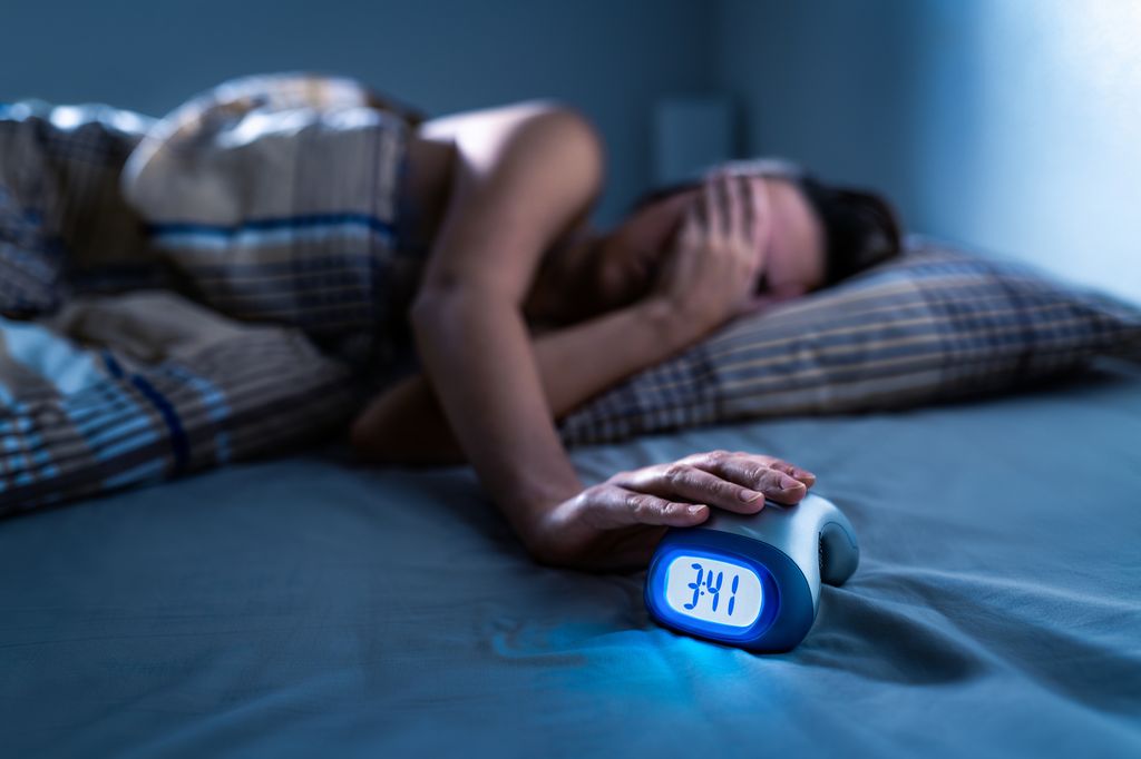 Woman trying to sleep in the middle of the night with clock light