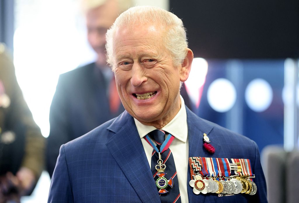 King Charles grinning with medals on blazer