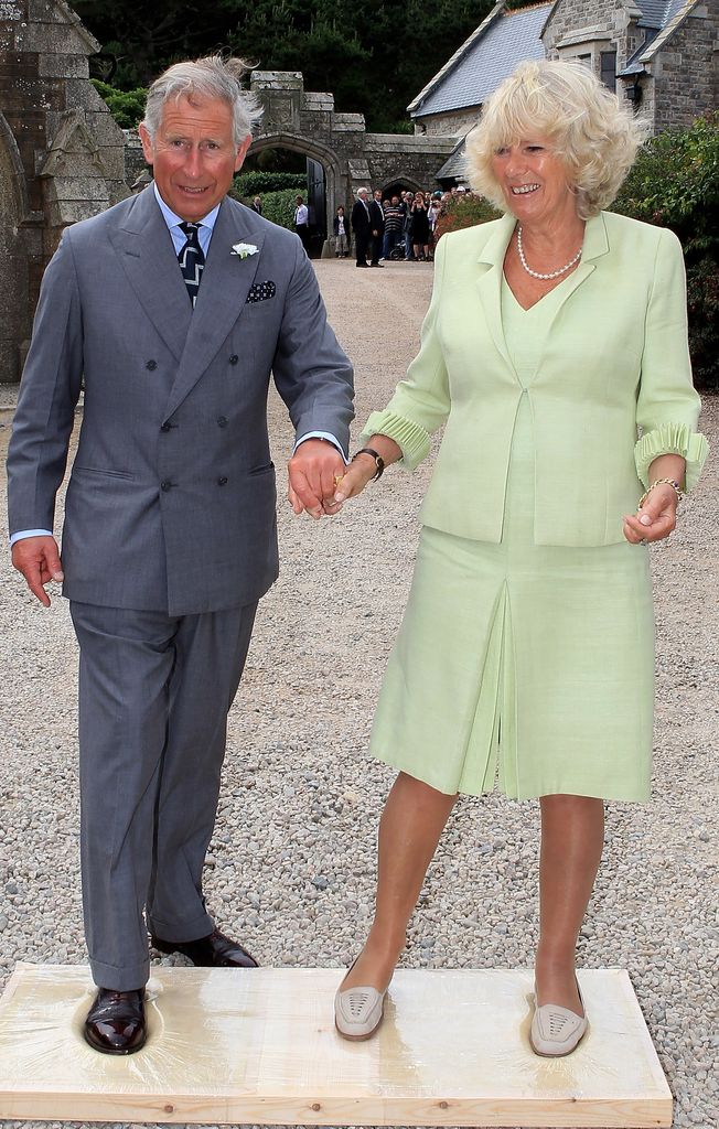 Charles and Camilla hold hands as they make imprints of their feet for a cast as they visit St Michaels Mount