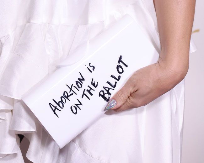 white clutch bag featuring abortion is on the ballot text in black