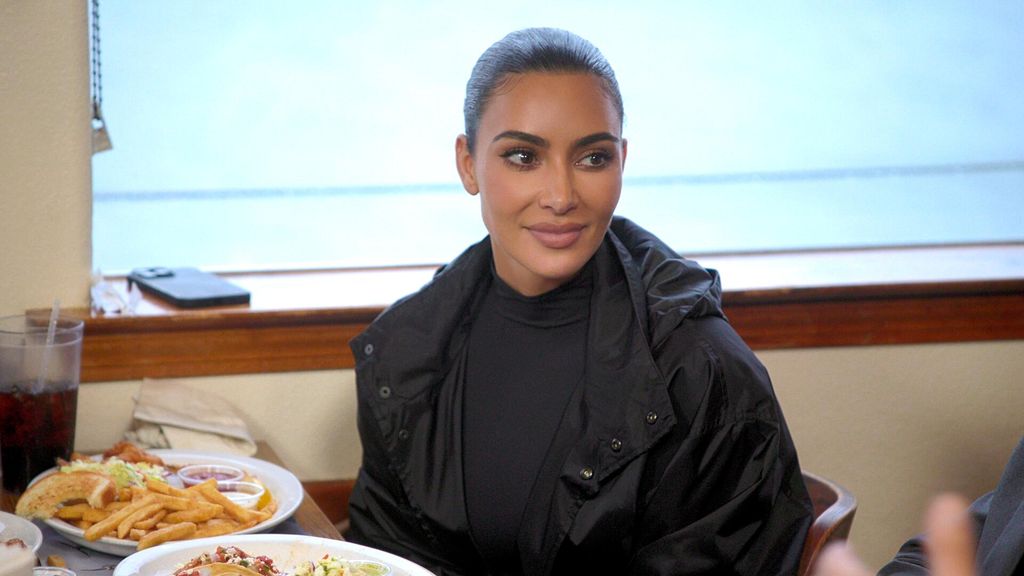 Kim Kardashian sits in a diner at a booth 