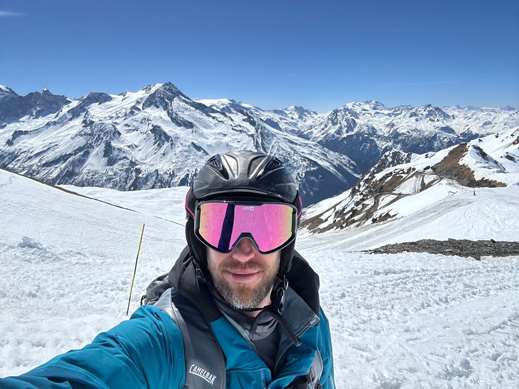 Skier taking  a selfie in a blue jacket with pink goggles