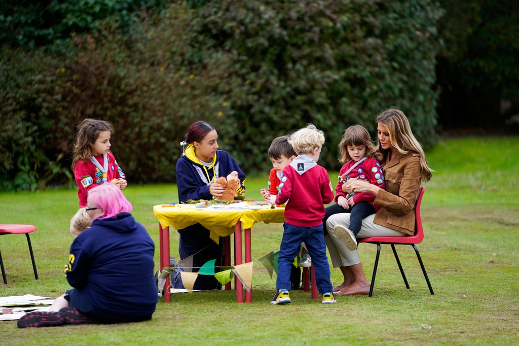 Melania Trump at a table of children with one sitting on her lap