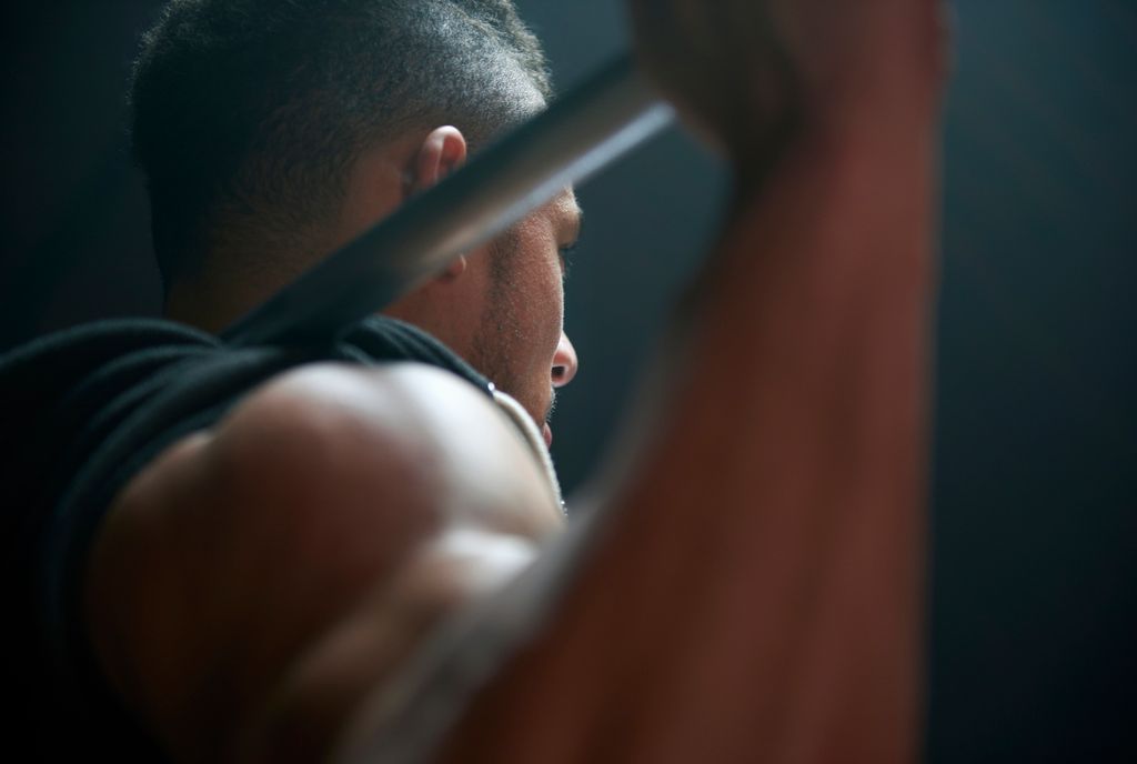 Athlète masculin soulevant la barre de poids fond noir
