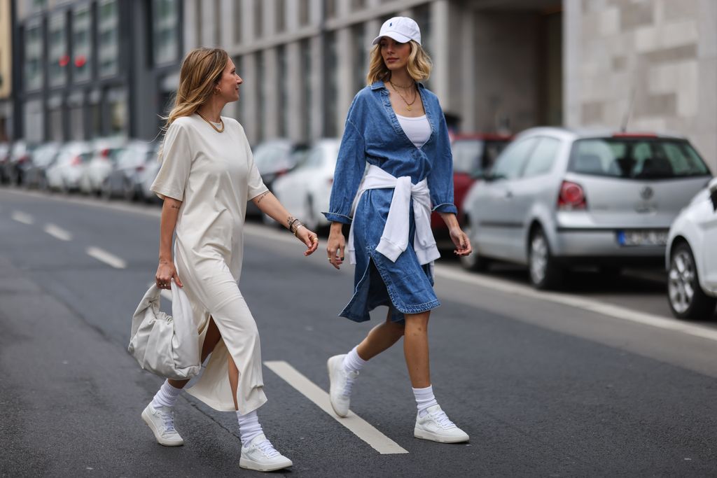 Justine SchlÃ¼tter wearing blue denim Mango dress, white Zara hoodie and white Copenhagen Studios sneakers and Michi Brandl wearing beige COS t-shirt dress, white Bottega Veneta leather bag and white Copenhagen Studios sneakers