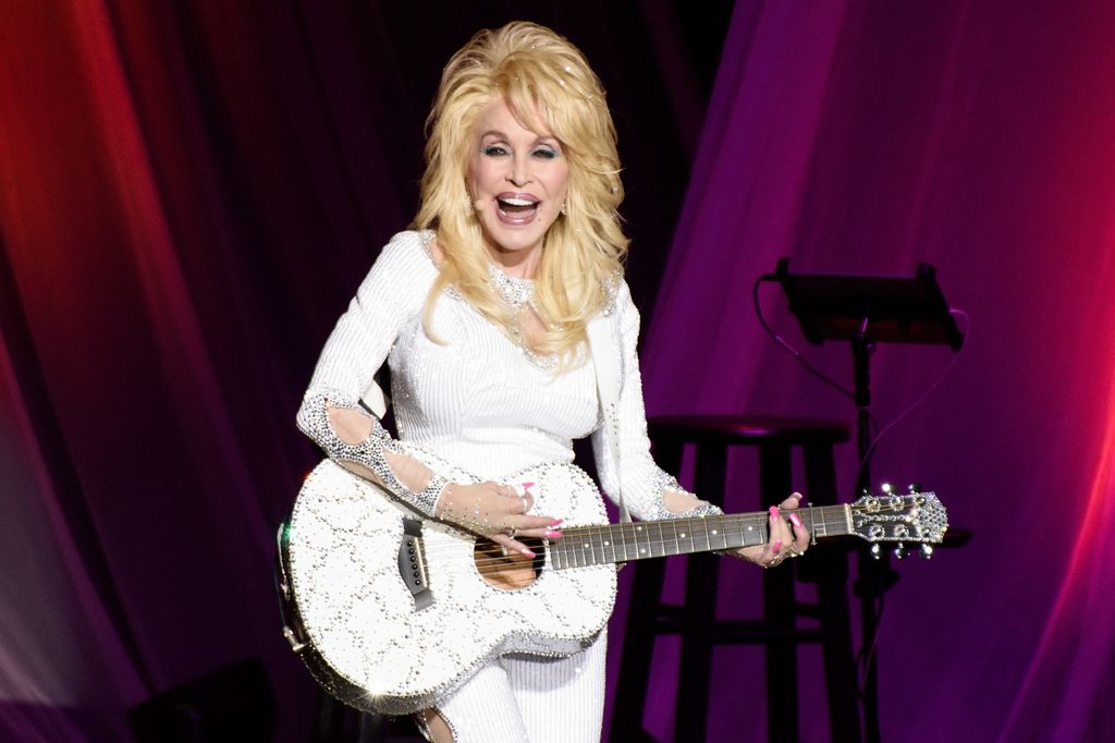 Dolly Parton in all-white outfit playing white guitar