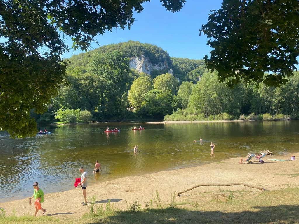 People by and on a river with cliffs and trees in the background