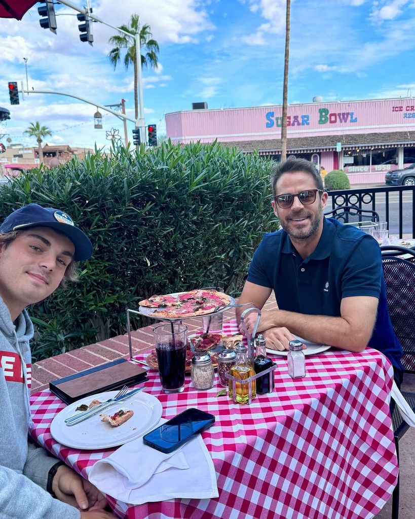 two men eating pizza outside 