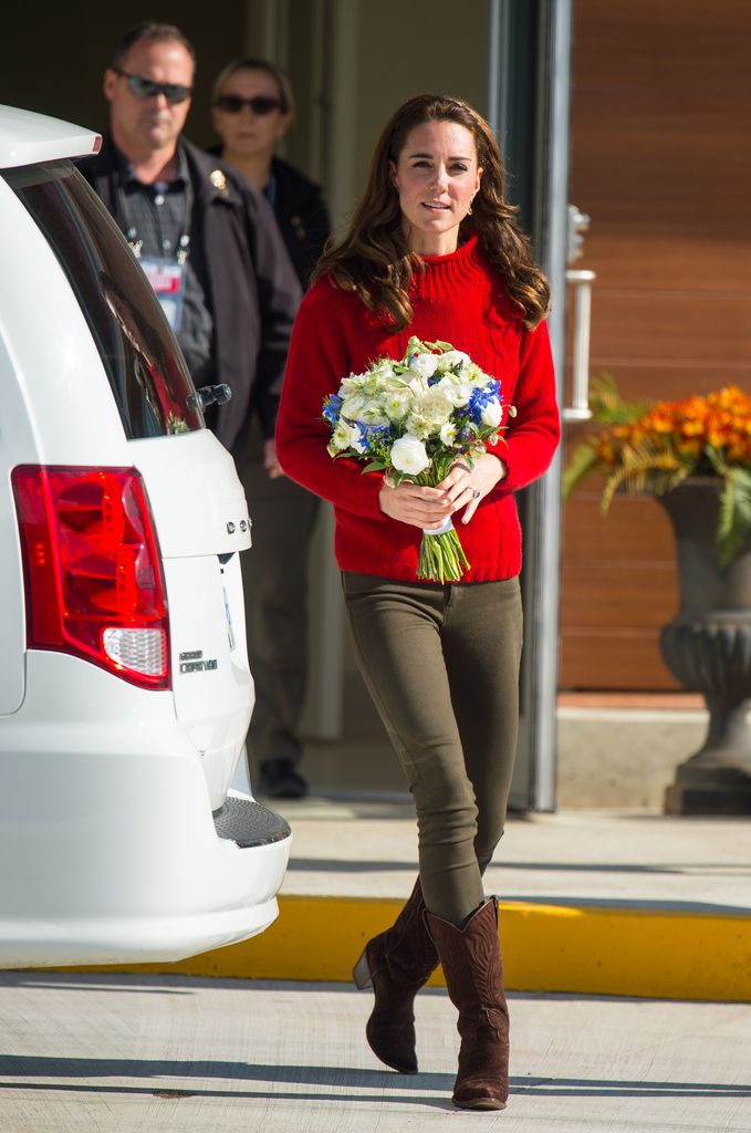 Kate in khaki jeans and red jumper holding bouquet