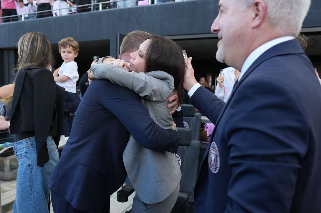 Victoria and david beckham hugging in suits