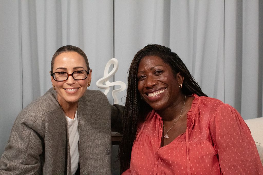 Two women in a podcast studio smiling 
