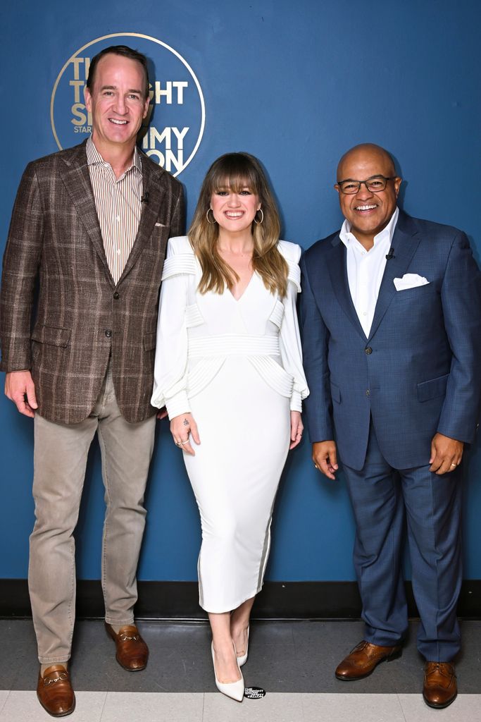 Kelly Clarkson posing with Peyton Manning and Mike Tirico 
