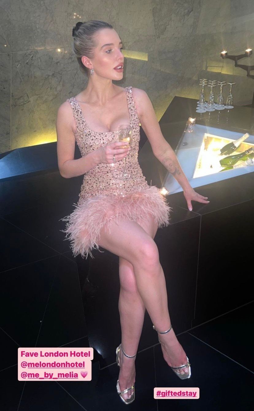 Helen drinking champagne in a low-cut gold sparkling minidress with 