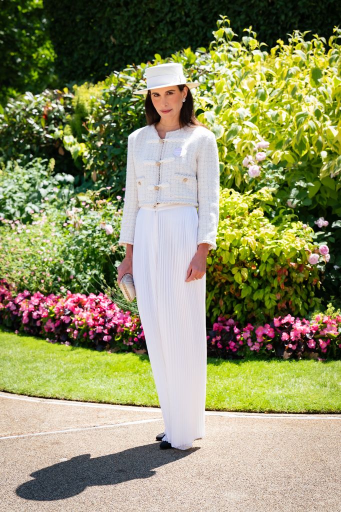 Caroline Sieber wears a white boucle jacket, pleated white skirt, and cream boater hat with a clutch bag at Royal Ascot.